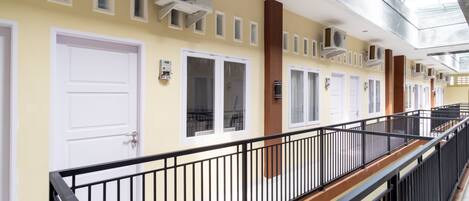 A corridor with multiple doors, air conditioning units, and a glass ceiling.