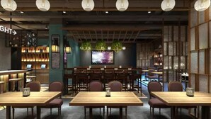 A restaurant with multiple wooden tables and chairs, a bar area with shelves of bottles, and a large screen on the wall. - Happy Dragon City Culture Hotel (Tian'AnMen Forbidden City) (Beijing)
