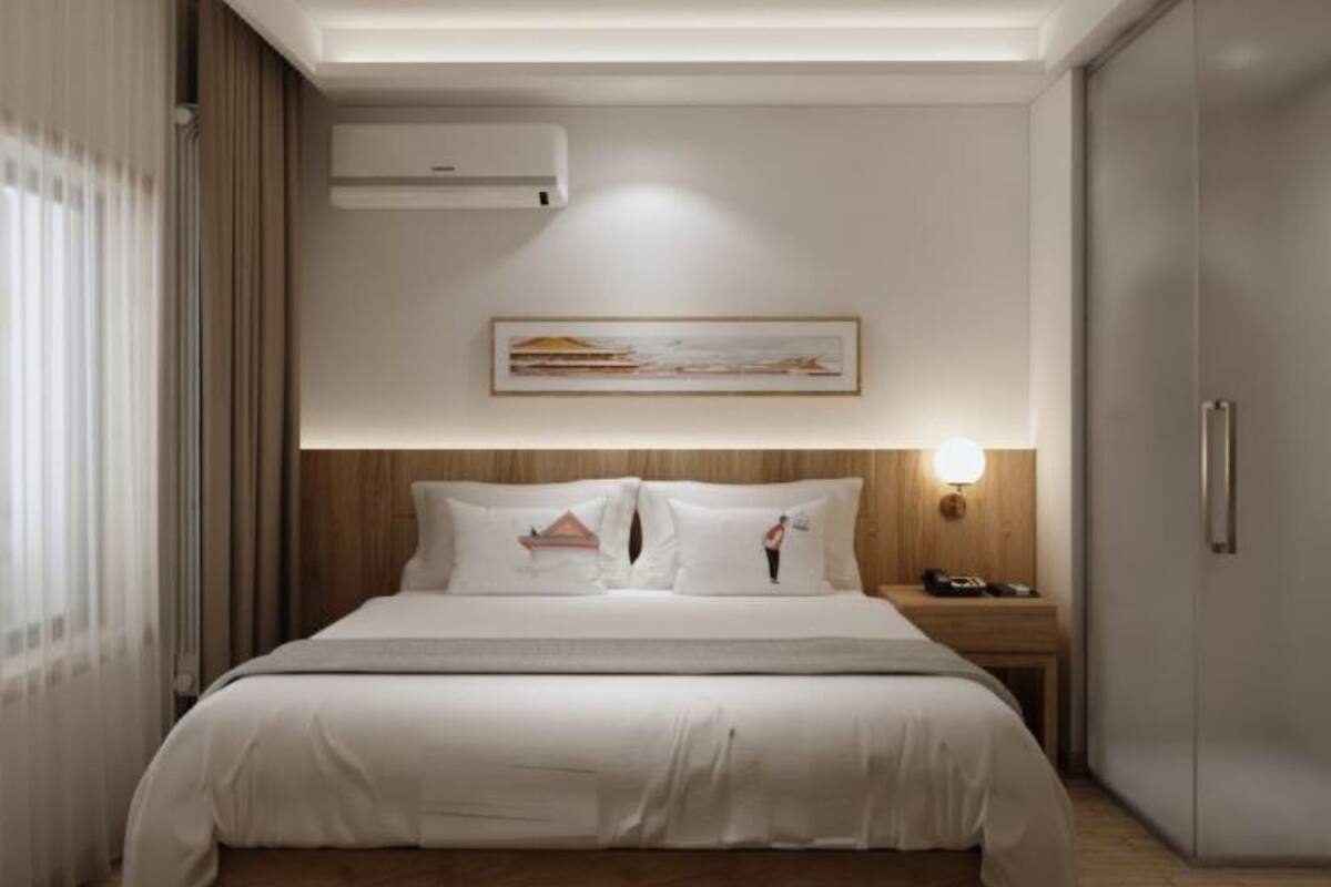 Une chambre d’hôtel moderne équipée d’un lit, d’une table de chevet, d’un climatiseur et d’une armoire.