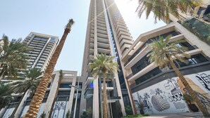 A tall, modern building with multiple floors, surrounded by palm trees and featuring a mural on one side. - Fantastay Blvd Crescent (Dubai)