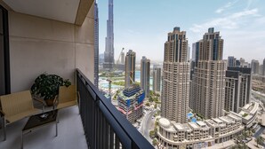 A balcony with wicker chairs and a potted plant, overlooking a cityscape with high-rise buildings and a construction site. - Fantastay Blvd Crescent (Dubai)
