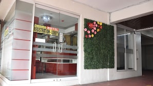 Ein Hotel Eingang mit einer Rezeption, einer Schiebetür und einer Wand mit Blumen.