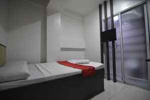 A hotel room with a bed, a TV mounted on the wall, and a sliding door. - Cosmo Hotel - Kamuning (Quezon City)