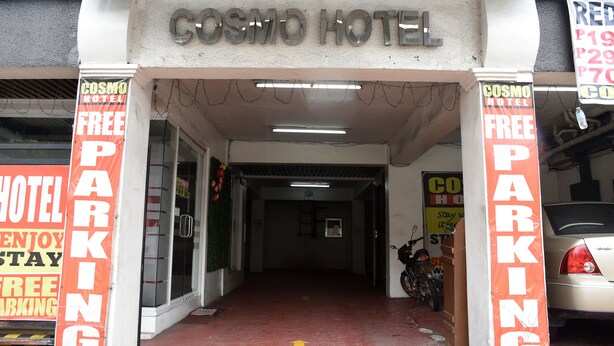 Der Eingang zum Cosmos Hotel mit Schildern, die kostenlose Parkplätze bewerben.