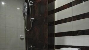 Ein Badezimmer mit Dusche, Toilette und Fliesen.