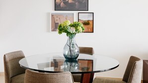 A round glass table with a vase of green flowers, surrounded by wicker chairs. - Fantastay Laguna Tower (Dubai)