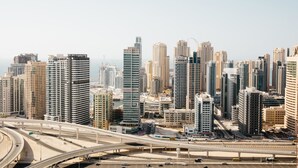 A cityscape with high-rise buildings, a highway, and a body of water. - Fantastay Laguna Tower (Dubai)