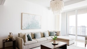 A modern living room with a beige sofa, a coffee table, and a chandelier. - Fantastay Laguna Tower (Dubai)