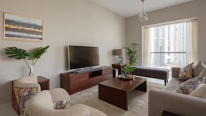 A modern living room with a flat-screen TV, a sofa, a coffee table, and a large window with a city view. - Fantastay Marina Tower (Dubai)