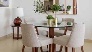 A dining area with a glass table surrounded by four chairs, a lamp, and potted plants. - Fantastay Marina Gate Tower (Dubai)
