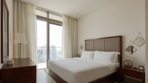 A hotel room with a large bed, a bedside table, a lamp, and a view of the city through the window. - Fantastay Marina Gate Tower (Dubai)