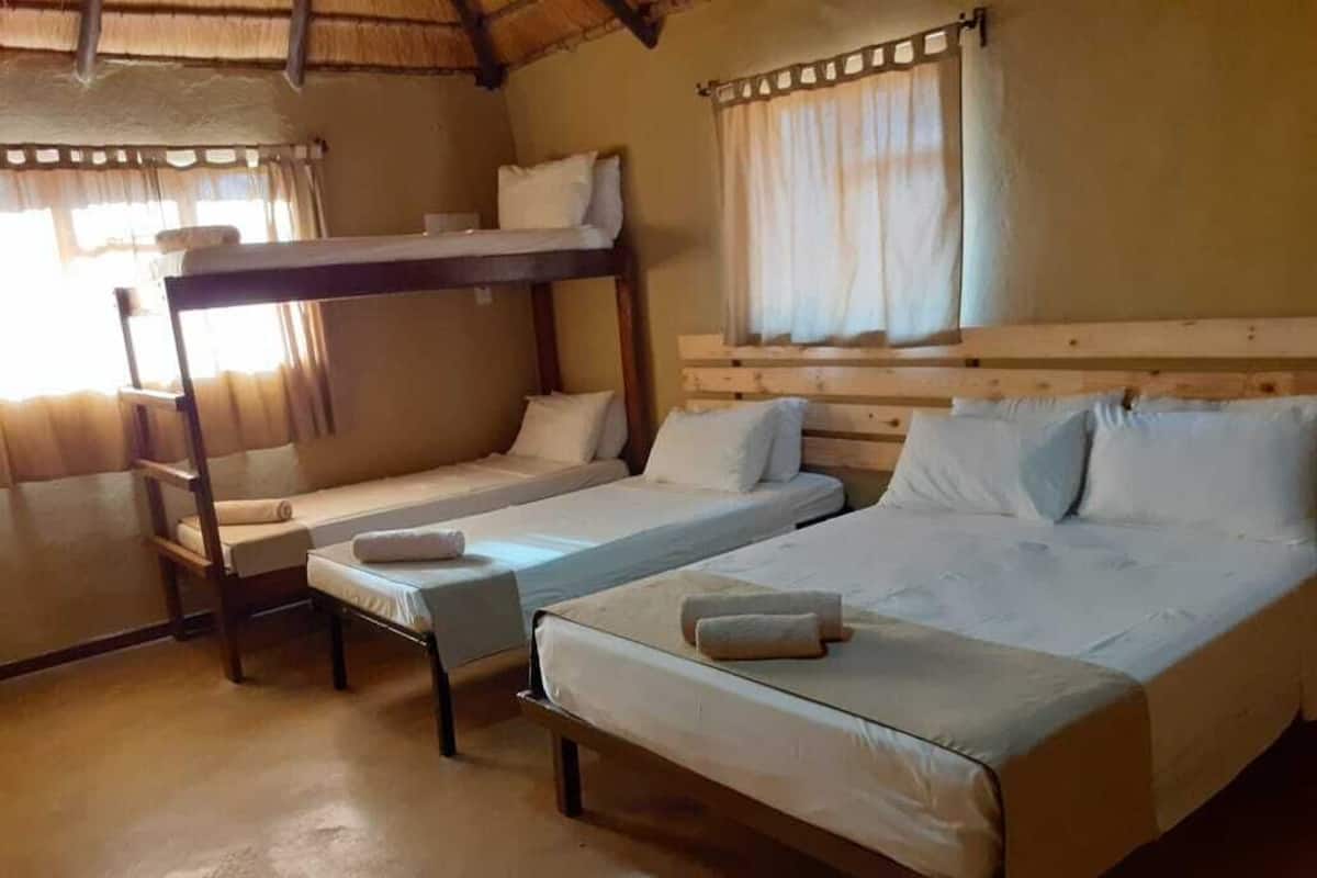 Une chambre avec des lits superposés et un lit simple, une tête de lit en bois et une fenêtre avec des rideaux.