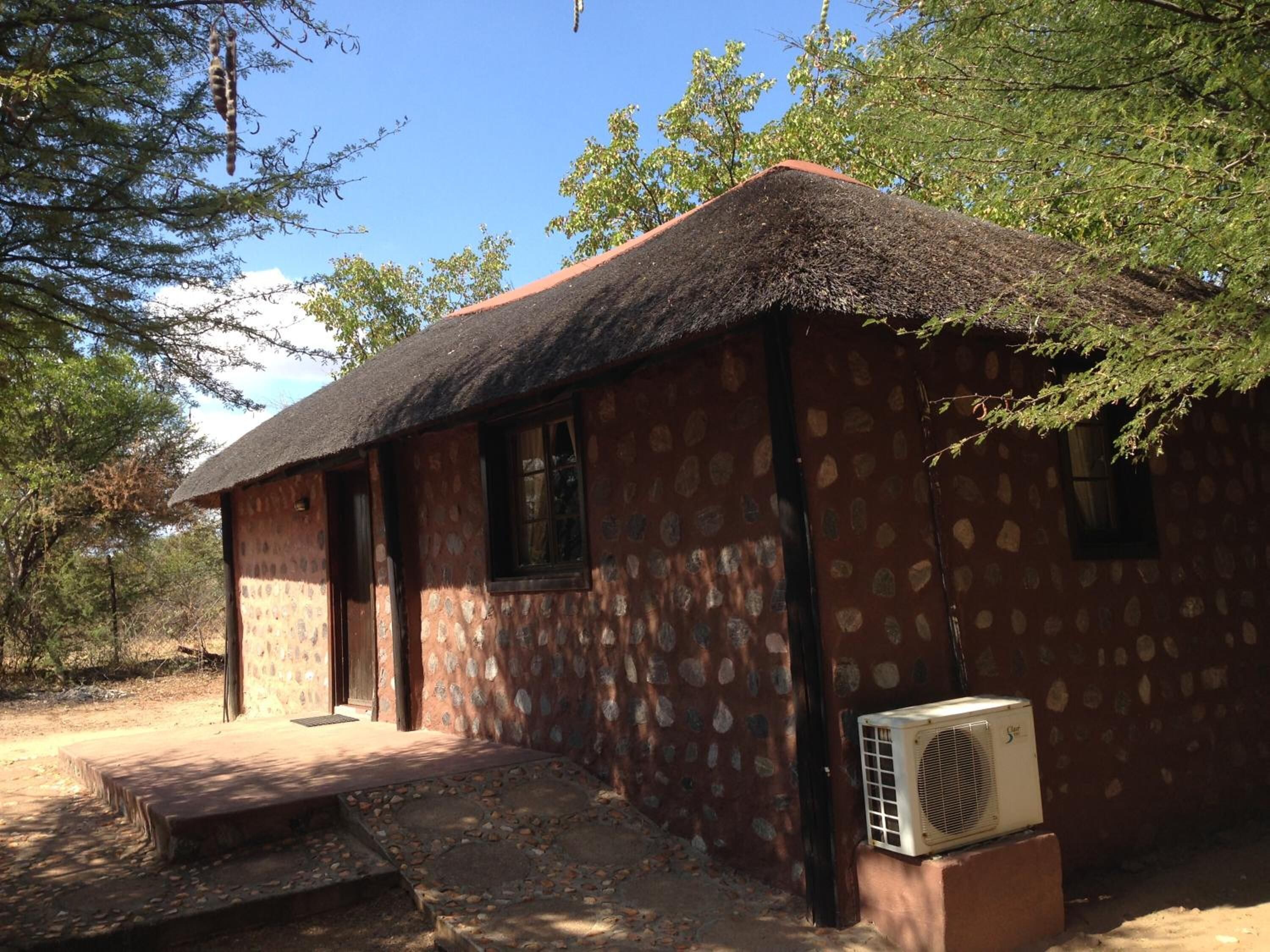 Un bâtiment rustique avec un toit de chaume, des murs en pierre et un petit porche.