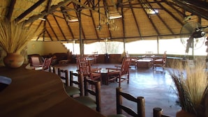 A rustic dining area with wooden furniture and a thatched roof. - Phokoje Bush Lodge (Selebi-Phikwe)