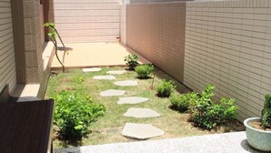 Un patio con un camino empedrado, plantas pequeñas y una maceta.