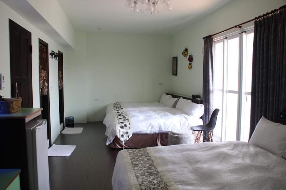 A hotel room with two beds, a desk, and a chair.