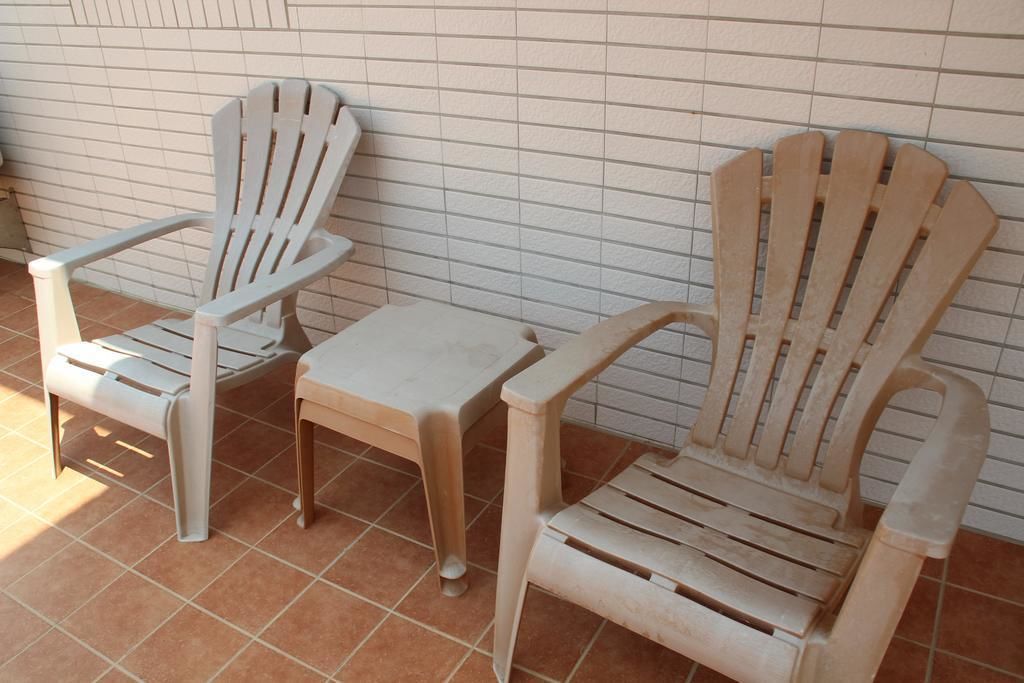 Dos sillas Adirondack de madera y una pequeña mesa frente a una pared de azulejos.