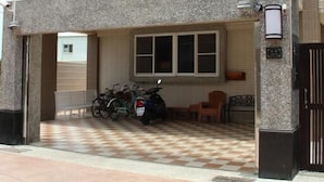 Una casa moderna de dos pisos con un garaje cubierto, una bicicleta estacionada afuera y un acceso con portón.