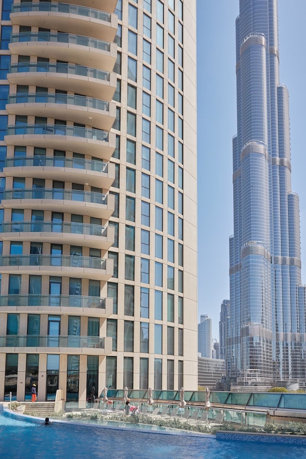 A modern building with a pool area, featuring a large glass facade and a distinctive curved balcony design.