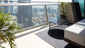 Un balcon offrant une vue sur le Burj Khalifa, un espace de vie moderne avec un canapé, une table en verre et une plante en pot.