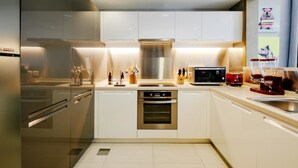 A modern kitchen with stainless steel appliances, a built-in oven, and a microwave. - FantaStay Claren Tower 1 (Dubai)