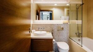 A modern bathroom with a wooden vanity, a white sink, a toilet, and a glass-enclosed shower area. - FantaStay Claren Tower 1 (Dubai)
