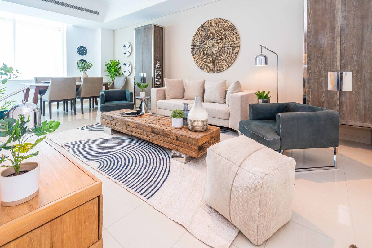 A modern living room with a sofa, coffee table, and a dining area with chairs and a table.