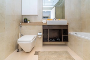 A modern bathroom with a toilet, sink, and bathtub. - FantaStay Botanica Towers (Dubai)