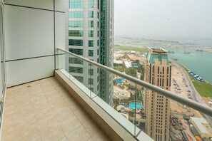 A balcony with a view of a high-rise building, a swimming pool, and a marina. - FantaStay Botanica Towers (Dubai)