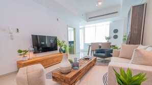 A modern living room with a flat-screen TV, a wooden coffee table, a beige sofa, and a potted plant. - FantaStay Botanica Towers (Dubai)