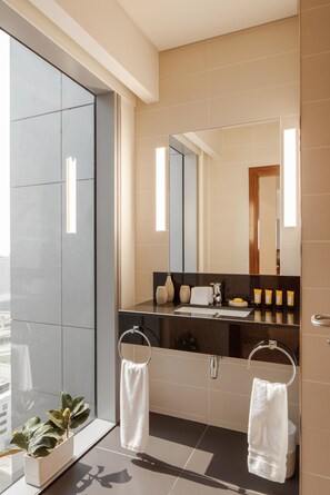 A modern bathroom with a large mirror, two towel rings, a sink, and a potted plant. - Fantastay Central Park Towers DIFC (Dubai)