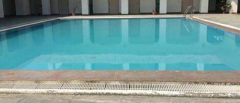 Een buitenzwembad, parasols bij het zwembad en ligstoelen