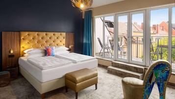 Une chambre d’hôtel avec un grand lit, un banc, une chaise et une vue sur l’extérieur.