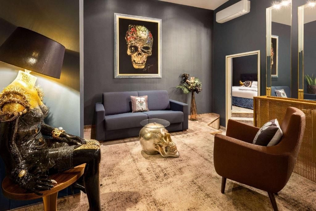 Una habitación con sofá, una silla, una escultura de calavera y una obra de arte con motivo de calavera en la pared.