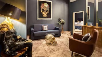 Una habitación con sofá, una silla, una escultura de calavera y una obra de arte con motivo de calavera en la pared.