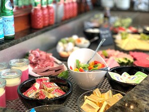 A buffet with various food items including meats, vegetables, and condiments. - Amedia Leipzig, Trademark Collection by Wyndham (Leipzig)