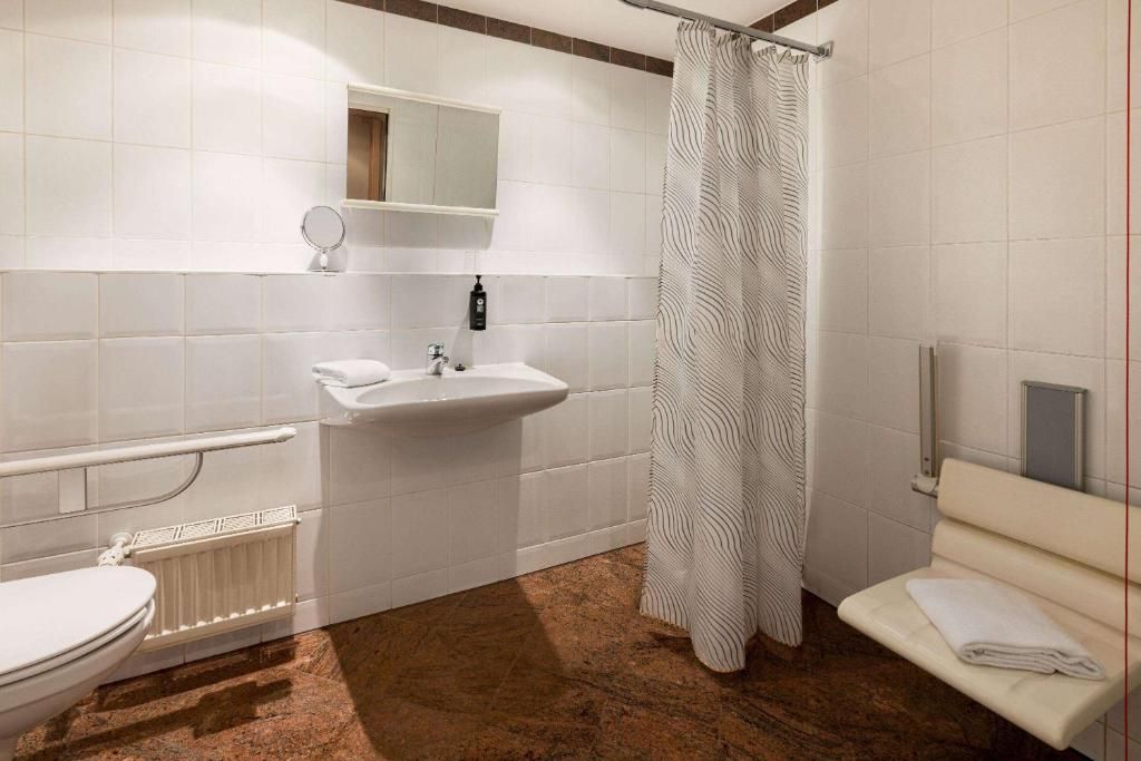 A bathroom with a toilet, sink, and shower curtain.