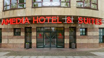 A hotel entrance with a sign reading "AMEDIA HOTEL & SUITES".