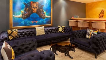 A dark blue tufted sofa set with a glass coffee table and a decorative animal sculpture.
