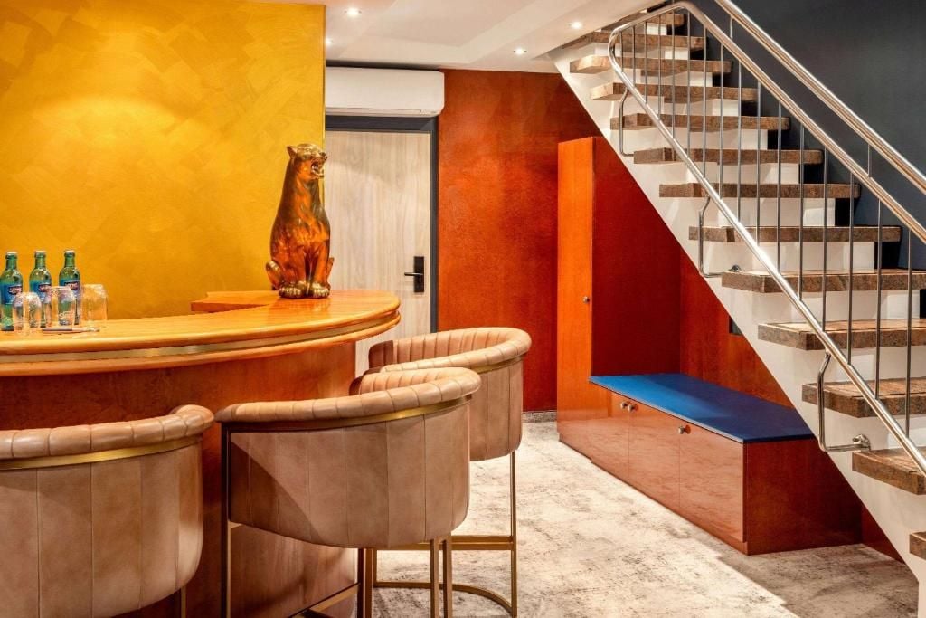 A modern interior with a curved bar area, plush seating, and a staircase with a metal railing.