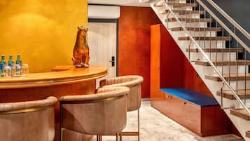 Un interior moderno con una barra curvada, sillones de cuero, una escalera y un banco de madera.