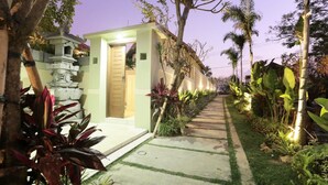 A pathway leading to a building with a traditional architectural style, surrounded by lush tropical plants and a well-maintained garden. - Kubu Kulat Villa (Pecatu)