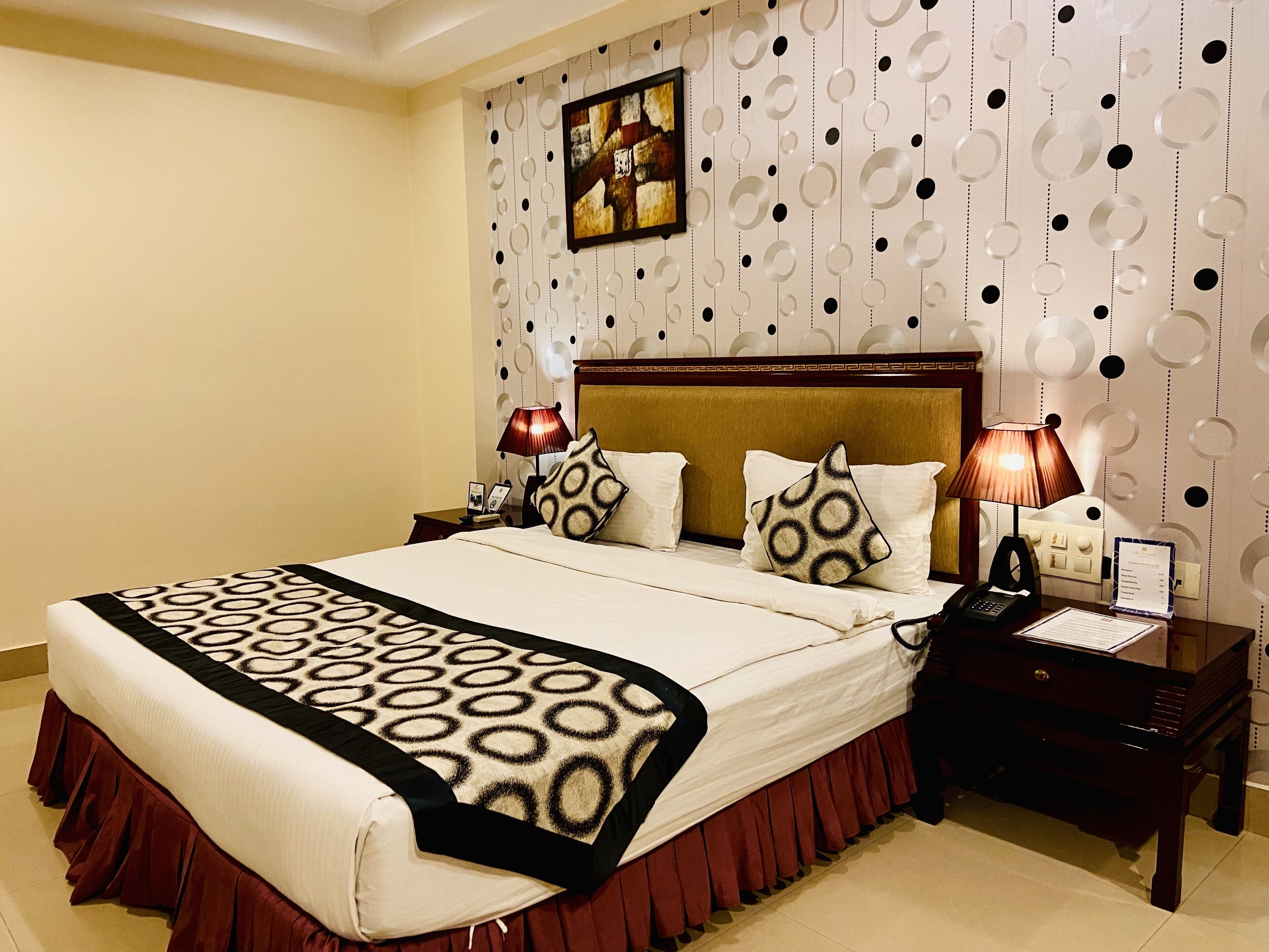 Habitación de hotel con una cama grande, dos mesitas de noche, un cabecero y una pared con diseños circulares.