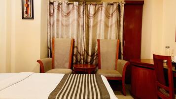 Een hotelkamer met een bed, twee fauteuils, een tafeltje en een bureau.