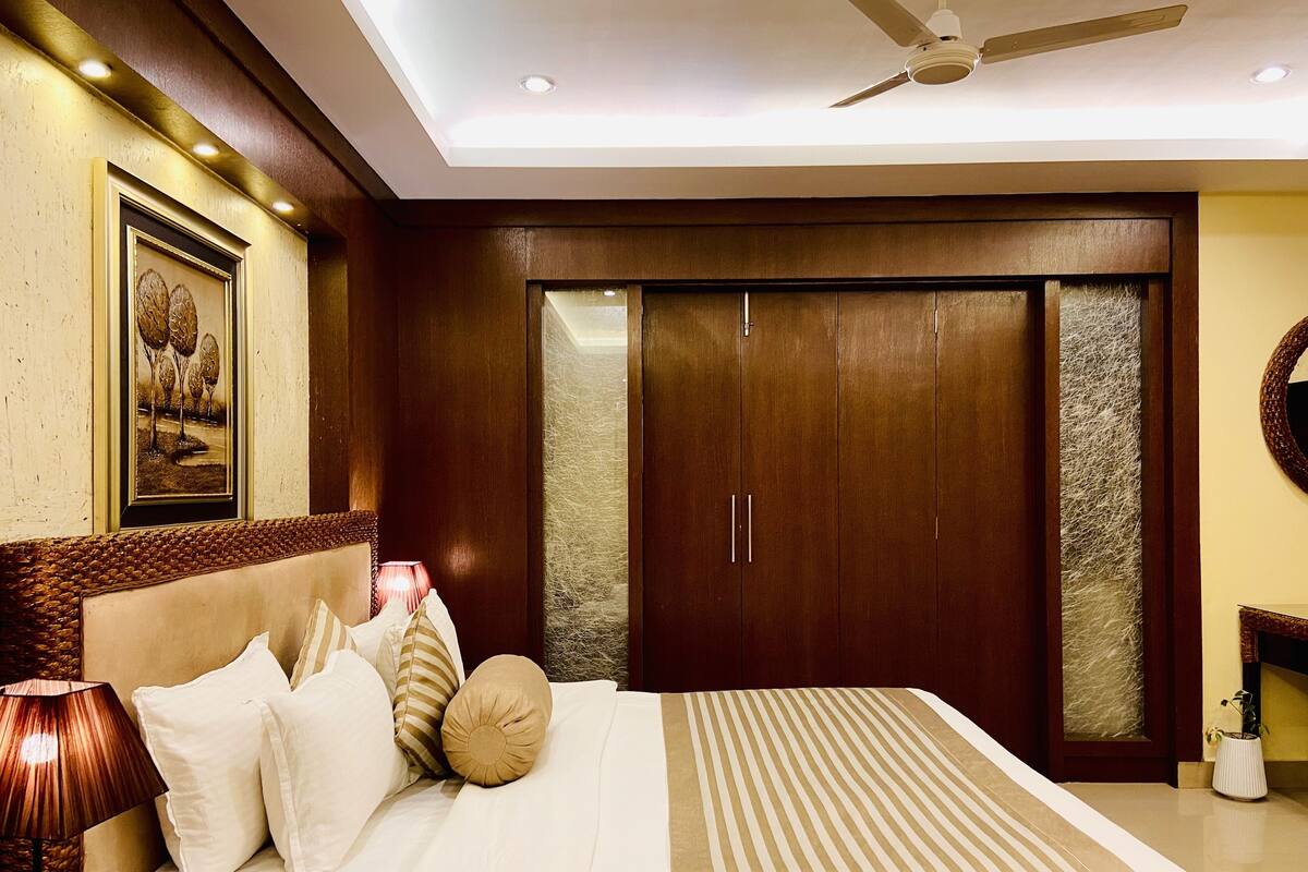 A bedroom with a bed, a nightstand, a lamp, a ceiling fan, and a wardrobe.