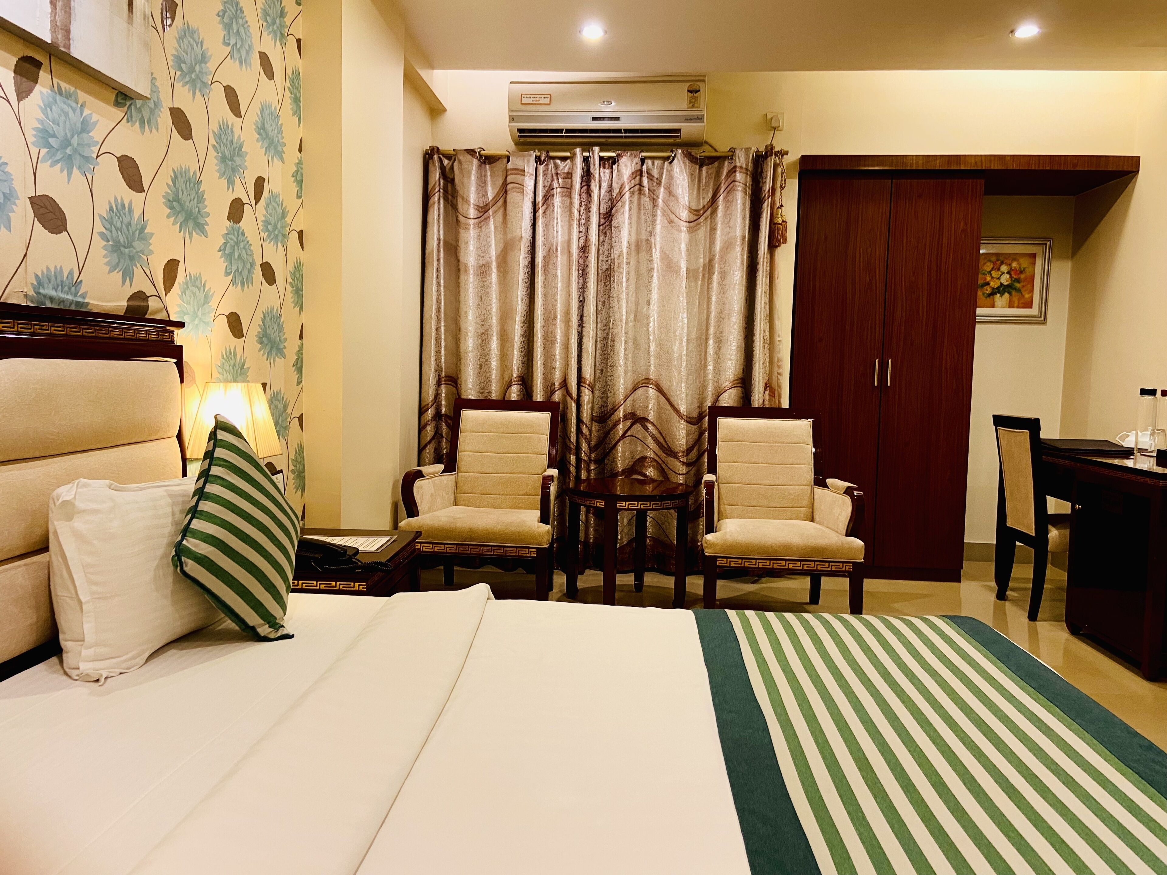 Habitación de hotel con cama, dos sillones, un escritorio y un armario.