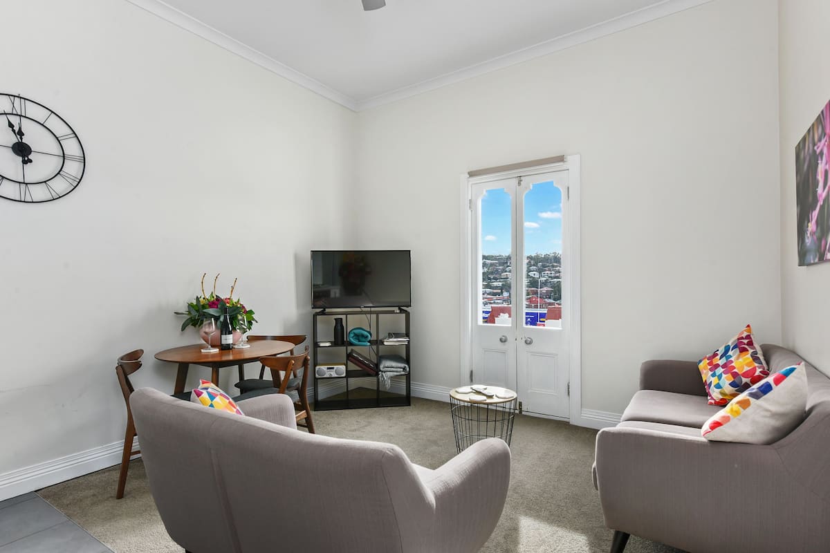 A living room with a flat-screen TV, two sofas, a coffee table, and a dining table with chairs.