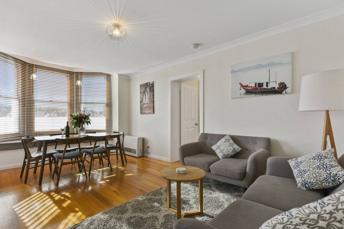 A living room with a grey sofa, a round coffee table, and a dining area with a table and chairs.