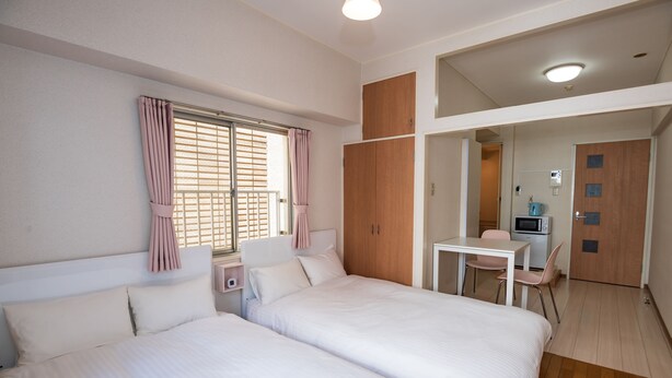 A hotel room with two beds, a desk, a chair, and a kitchenette. - Fukuoka Haneul inn (Fukuoka)