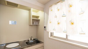 A bathroom with a sink, mirror, and window with floral curtains. - Fukuoka Haneul inn (Fukuoka)
